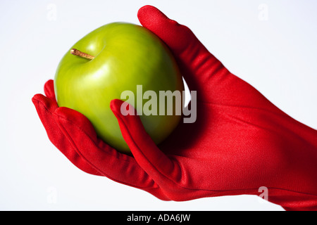 Green appel tenuto in mano con red glove Foto Stock