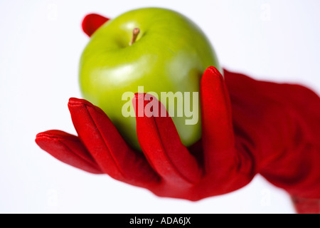Green appel tenuto in mano con red glove Foto Stock