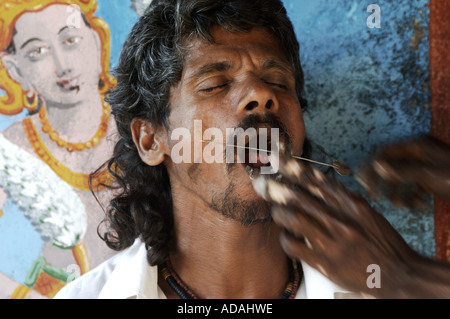 Kataragama un pellegrino indù perforare il suo volto con un perno di ferro come un auto castigo rituale per il dio indù Skanda Foto Stock