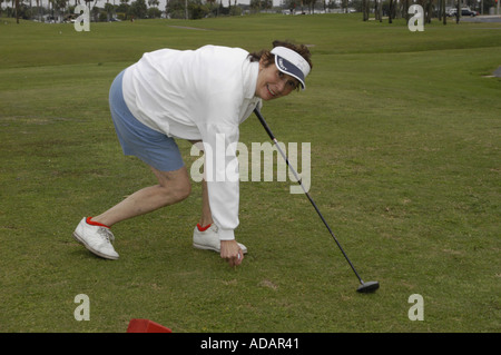 Senior donna posizionando la pallina da golf sul raccordo a T Foto Stock
