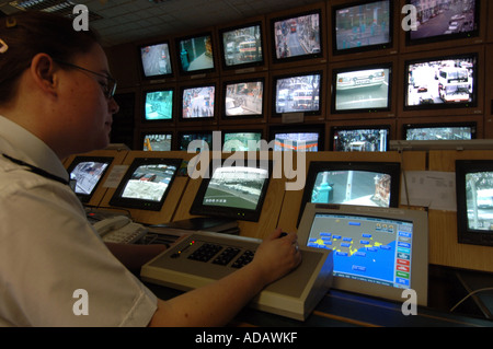 Un operatore TVCC a Brighton stazione di polizia controlla una banca di schermi da telecamere CCTV monitoring per le strade della città Foto Stock