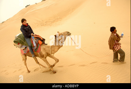 Essendo turistici portano attraverso il deserto su un cammello trek in Jaisalmer rajasthan vicino al confine pakistano Foto Stock