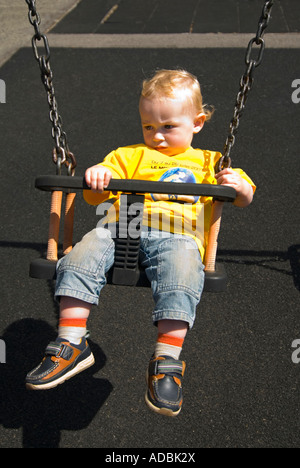 Chiudere verticale su ritratto di una modesta 16 mese vecchio baby boy stanchi dopo essere stato spinto sul oscilla in un parco Foto Stock