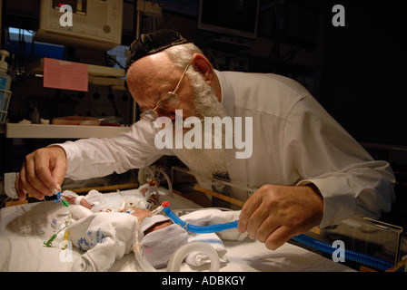 Un medico Haredi che controlla il neonato prematuro in un incubatore presso l'unità di terapia intensiva neonatale del Centro medico Share Zedek di Gerusalemme ovest Israele Foto Stock