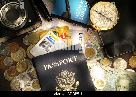 Denaro da viaggio e carte di credito concetto con passaporto valuta estera e monete una bussola e fotocamera digitale Foto Stock