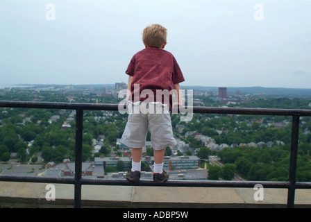 Piccolo bambino guarda fuori su una ringhiera presso la città di New Haven Connecticut USA in cima est Rock City Park Foto Stock