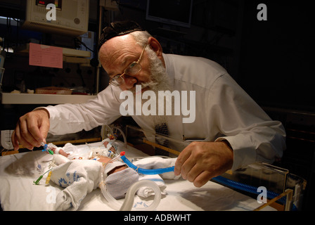 Un medico Haredi che controlla il neonato prematuro in un incubatore presso l'unità di terapia intensiva neonatale del Centro medico Share Zedek di Gerusalemme ovest Israele Foto Stock