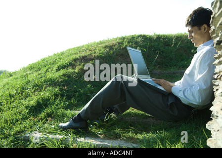 Imprenditore seduto a terra, utilizzando laptop Foto Stock