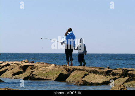 Una giovane madre con bambino cammina lungo un pontile per andare a pesca Foto Stock