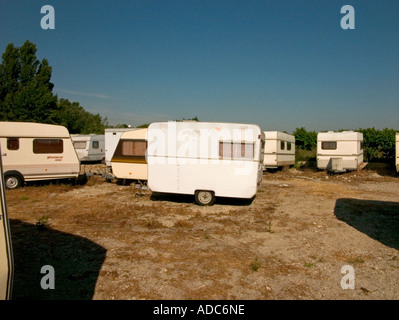 Una serie di vecchie e nuove roulotte giacciono sparsi attorno a un campo abbandonato Foto Stock