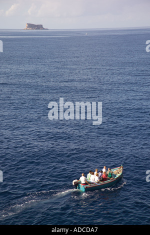 Barca di ritorno da un viaggio per la Grotta Blu al largo della costa di Isola di Filfla in distanza Foto Stock