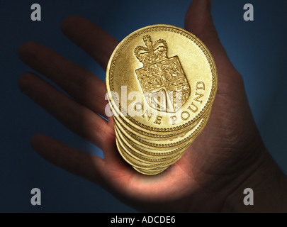 Mano che tiene la risma di UK Pound monete Foto Stock