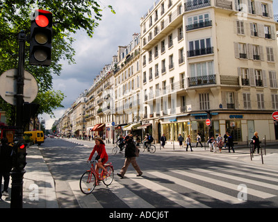 Scena di strada con la donna in abito rosso su rosso bicicletta attraversando via parigi francia Foto Stock