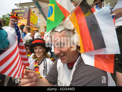 Un appassionato di calcio che indossa una è stata una palla di cuoio con vari flag fissato come un cappello a una coppa del mondo di calcio pubblico visualizzazione Evento Foto Stock