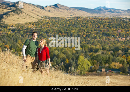 Coppia caucasica guardare escursione attraverso tall golden autumn erba con le montagne Foto Stock