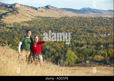 Coppia caucasica guardare escursione attraverso tall golden autumn erba con le montagne Foto Stock