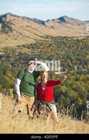 Coppia caucasica guardare escursione attraverso tall golden autumn erba con le montagne Foto Stock