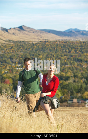 Coppia caucasica escursione attraverso tall golden autumn erba con le montagne Foto Stock