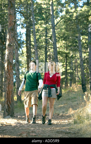 Felice coppia caucasica tenere le mani durante le escursioni sul sentiero natura attraverso gli alberi di pino Foto Stock