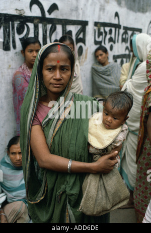 La madre del bambino che porta in coda per il cibo con altre donne a Madre Teresa di Calcutta missione India Foto Stock