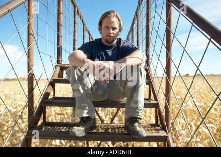 Uomo seduto sui gradini in un campo di mais Foto Stock