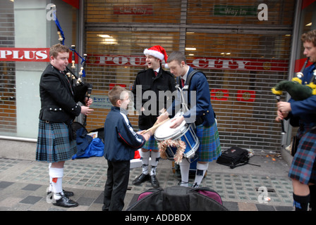 Ragazzo giovane suonando i tamburi di Scots Pipers il divertimento del pubblico alla vigilia di Natale. Sauchiehall Street. Glasgow. La Scozia. Foto Stock