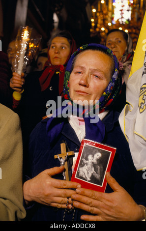 Ucraina, 1989; durante il primo servizio cattolico nella Chiesa della Trasfigurazione di Lviv dal 1946, una donna piange portando un crocifisso e immagini di Maria Gesù, accanto a lei una bandiera papale.29 Ott 1989 Foto Stock