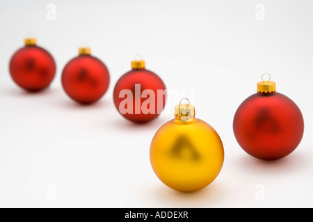 Guardando verso il basso su una d'oro albero di Natale ornamento della lampadina in linea con quattro lampadine rosso su sfondo bianco ritratto in studio Foto Stock