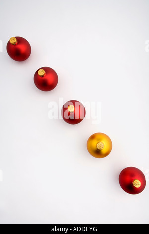 Guardando verso il basso su una d'oro albero di Natale ornamento della lampadina in linea con quattro lampadine rosso su sfondo bianco ritratto in studio Foto Stock