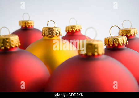 Primo piano di una d'oro albero di Natale ornamento della lampadina spicca tra i bulbi rosso impilati insieme su sfondo bianco ritratto in studio Foto Stock