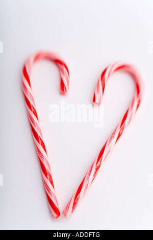 Primo piano di due Natale candy canne in forma di cuore sfocato in alto su sfondo bianco ritratto in studio Foto Stock