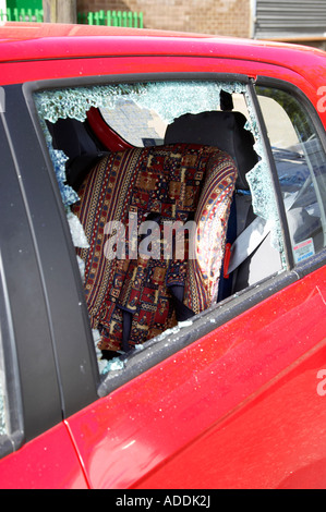 Fracassato posteriore lato passeggero finestra di red hyundai auto con bambini sedile auto visibile Foto Stock