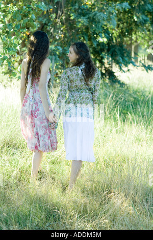 Giovani donne hippie camminare attraverso il campo, tenendo le mani Foto Stock