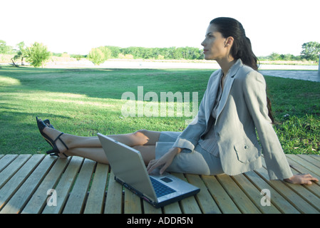 Imprenditrice seduta sul ponte con il computer portatile Foto Stock