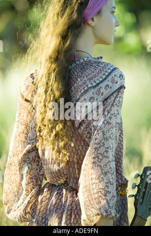 Giovane donna hippie tenendo la chitarra, vista posteriore Foto Stock