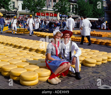 Paesi Bassi. Mercato del formaggio di Alkmaar. Coppia giovane in abiti tradizionali seduti sul bordo di formaggi. Foto Stock