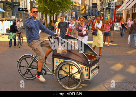 Un uomo a cavallo di un Christianiabike e parlando al telefono nel centro di Copenhagen Danimarca UE Foto Stock