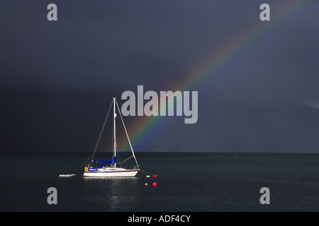 Un arcobaleno e meditabondo Dark Sky fare uno sfondo drammatico di barca sul Loch Nevis KNOYDART SCOZIA. Foto Stock