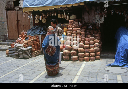 Donna di fronte della vecchia pentola di cottura shop nel mercato Sanaa Yemen Foto Stock