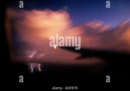 Questa foto è stata scattata dalla finestra di un aereo commerciale.Il fulmine colpisce da una tempesta cloud con piano ala in primo piano Foto Stock