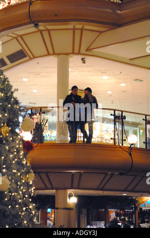 Coppia giovane appoggiata sulla ringhiera a Princes Square Shopping Centre, Glasgow.la Scozia. La Vigilia di Natale, Dicembre Foto Stock