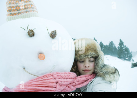 Teen ragazza abbracciando pupazzo di neve Foto Stock