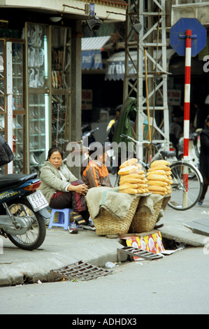 I fornitori di pane seduta in corrispondenza della zona di spigolo di Cau Go e Dinh Liet strade, Hanoi Old Quarter, Viet Nam Foto Stock