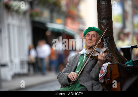 Il vecchio uomo irlandese di suonare il violino per il denaro in seduta tourist area pedonale di Temple Bar a Dublino Foto Stock