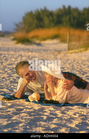 Romantica Coppia di mezza età che giace con le braccia intorno a ogni altro sulla sabbiosa spiaggia della Florida in estate Foto Stock