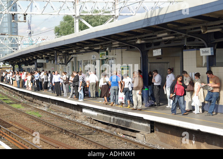 Stratford pendolari attendere sulla principale linea ferroviaria piattaforma di interscambio in serata durante le ore di punta Foto Stock