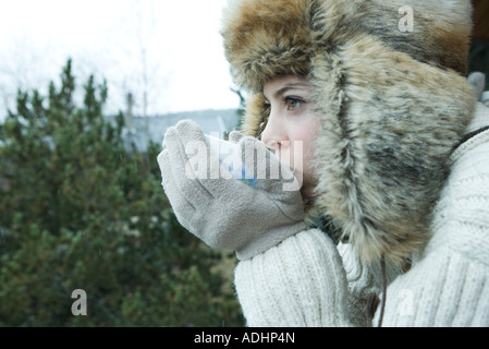 Teen ragazza di bere dalla ciotola in abbigliamento invernale Foto Stock