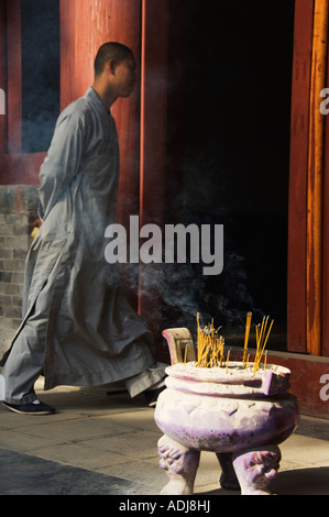 Un tempio monaco e bastoncini di incenso che brucia a Tempio Shaolin Kung Fu luogo di nascita di arti marziali Shaolin nella provincia di Henan in Cina Foto Stock
