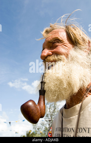 Grande EXUMA BAHAMA GEORGE TOWN uomo maturo in barba folta sbuffando sul tubo burled Nazionale della Famiglia Isola Celebrazione di Regata Foto Stock