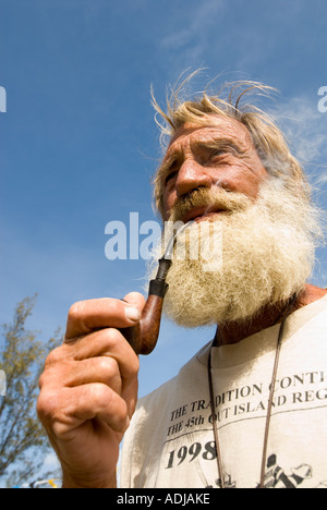 Maggiore EXUMA BAHAMA GEORGE TOWN uomo maturo in barba folta sbuffando sul tubo burled mentre la vela in Bahamas Foto Stock